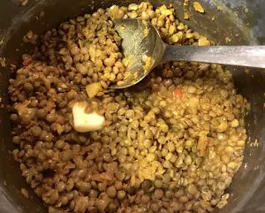 Cooked Green Lentils with butter and a spoon in a pot