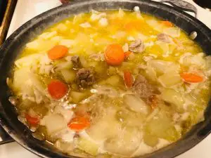 onions, carrots, potatoes, chicken, and water in a skillet