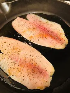 Seasoned tilapia fillets in a pan