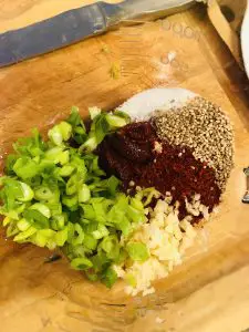 scallions, red pepper powder, red pepper paste, sesame seeds, sugar, garlic in a glass bowl