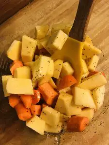 chopped rutabaga and chopped carrots with a spoon in a bowl