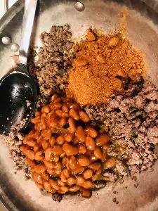 Beans, Beef, Taco Seasoning in a skillet with a spoon