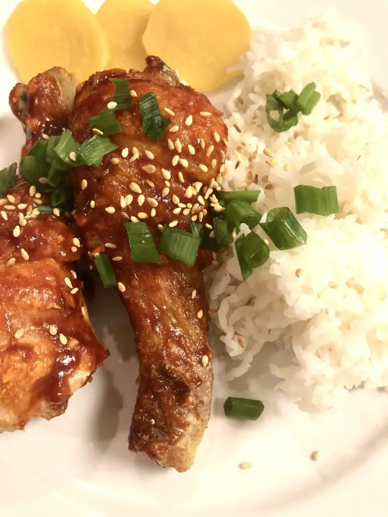 Korean Fried Chicken garnished with green onions sesame seeds and served with rice and daikon radish