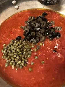 tomatoes, olives, and capers in a skillet