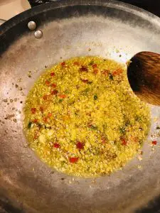 MInced garlic and chilies in oil in a skillet with wooden spoon