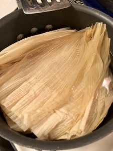 soaking corn husks in hot water in a pan