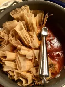 Mississippi Hot Tamales simmering in a liguid in a deep pan