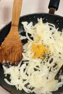 Onion, garlic, turmeric, salt and pepper in a nonstick pan with a wooden spoon