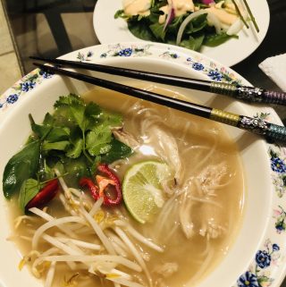 Pho Ga in a bowl with chopsticks and salad