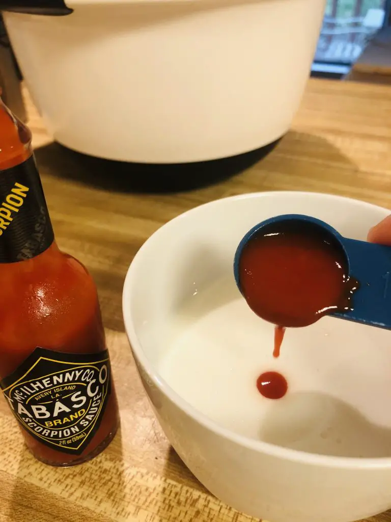 Buttermilk in a white cup and Tabasco scorpion sauce