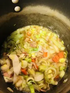 Chicken broth, leeks, potato, carrot, and cabbage in a large stockpot