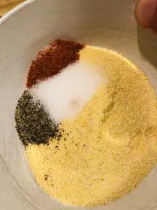 corn meal, cayenne, salt, and pepper in a white bowl