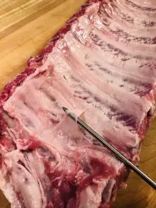 Baby back pork ribs with a sharp instrument to remove the membrane