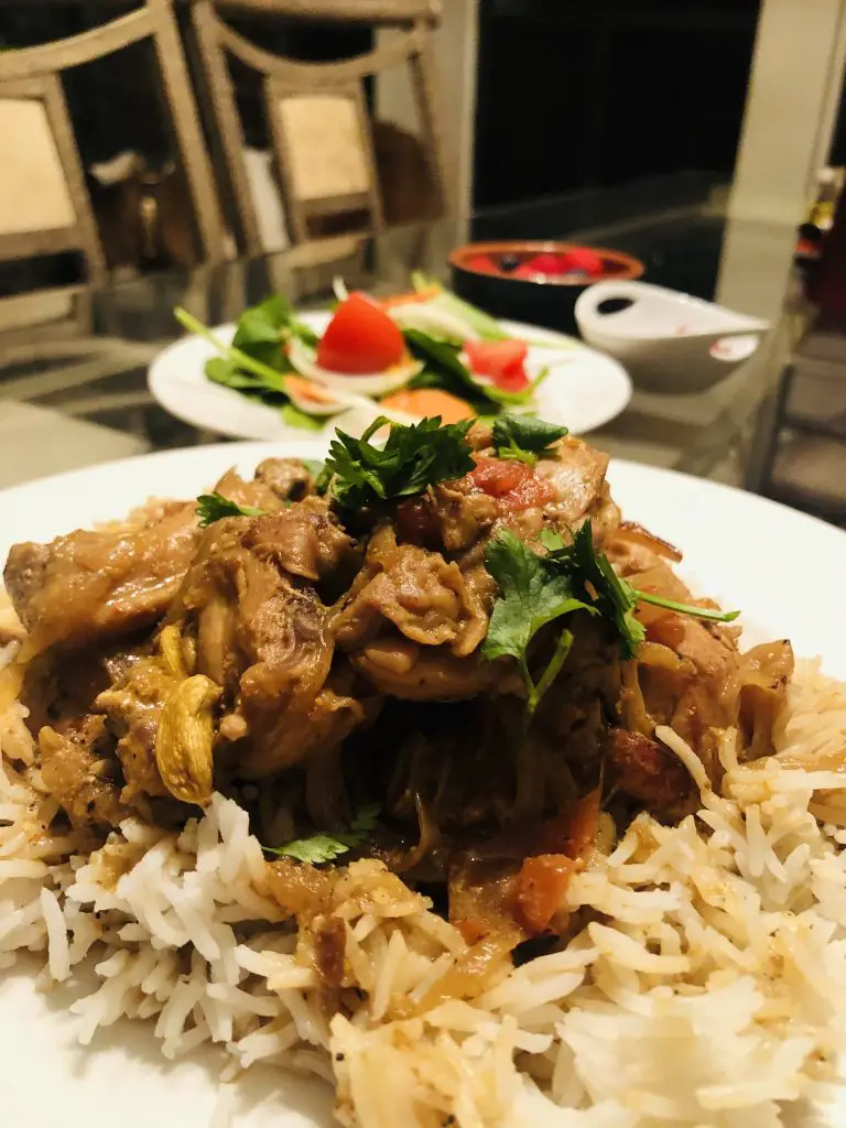 Chicken Biryani on a plate with salad in the background