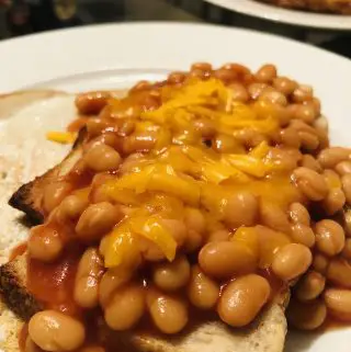 Cheddar cheese melting on beans on toast