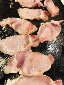 back bacon cooking on a griddle