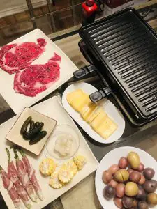 Raclette grill, steaks, prosciutto wrapped asparagus, raclette cheese, boiled new potatoes, gherkins, cocktail onions, sliced corn