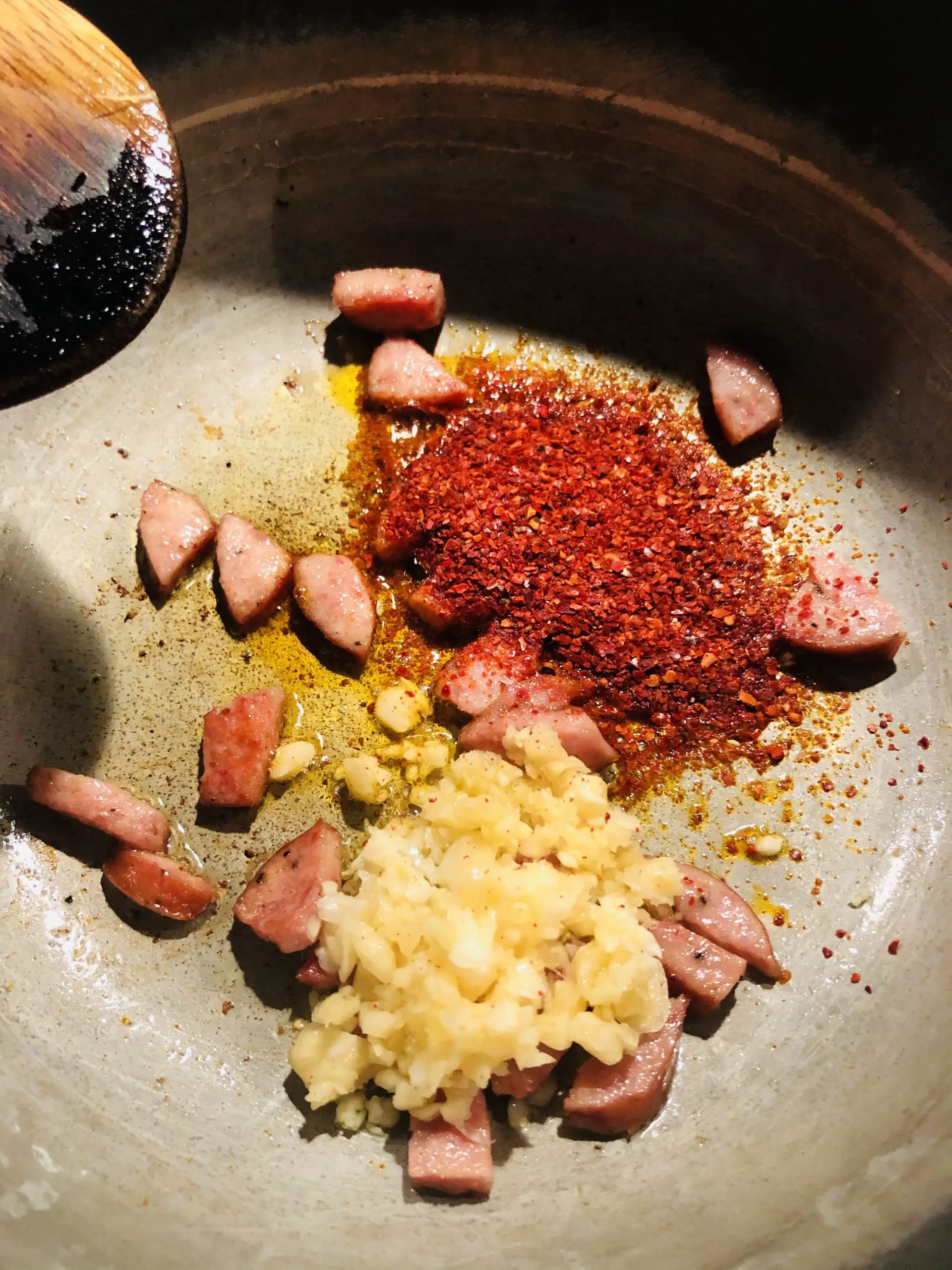 Garlic, sliced pork sausage, and gochugaru in a saucepan 