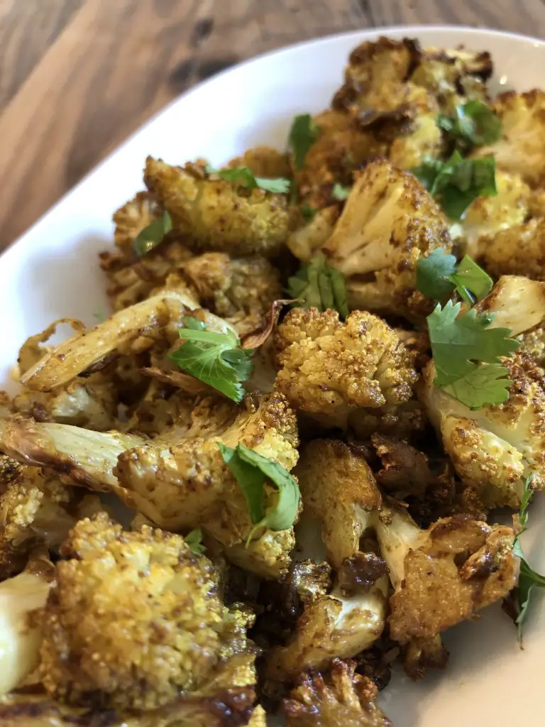 Indian Spiced Cauliflower garnished with cilantro in a white serving dish