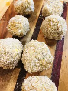 Boudin Balls which have been breaded displayed on a wooden board