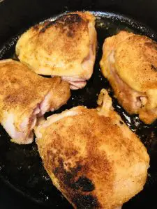 browned chicken thighs in a cast iron pan