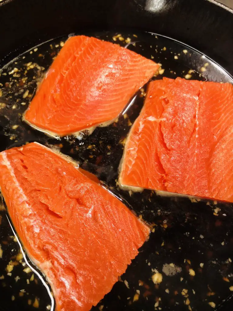 Salmon being poached in a cast iron pan
