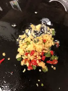 Garlic and thai chilies in oil in a cast iron pan