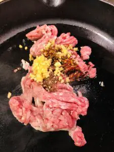 minced pork, garlic, and various seasonings in a cast iron pan