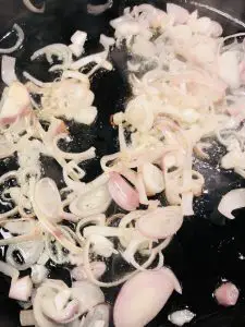 Sliced shallots in a cast iron pan