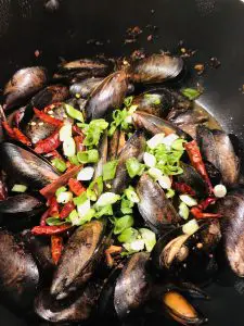 Mussels With Black Bean Sauce topped with dried Asian chilies and chopped green onions