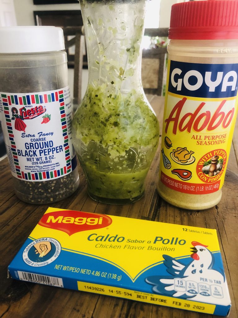 Black pepper, a bottle of Haitian epis, Goya Adobo seasoning, and maggi seasoning cubes