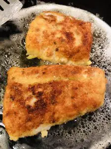 Cod frying in oil turning golden brown