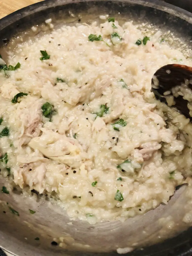 Chicken Risotto with parsley in a skillet with a wooden spoon