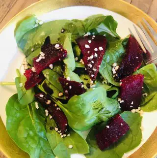Roasted Beets and Spinach Salad in a gold rimmed bowl with a fork on the side