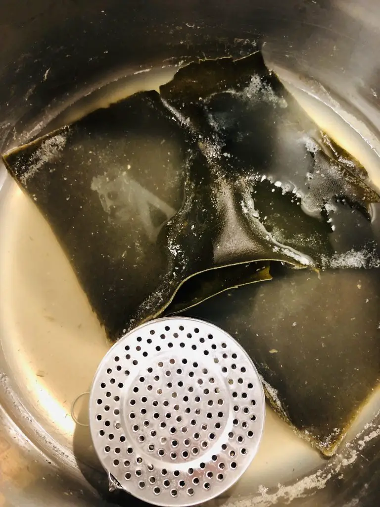 kelp soaking in water and an anchovy strainer next to it