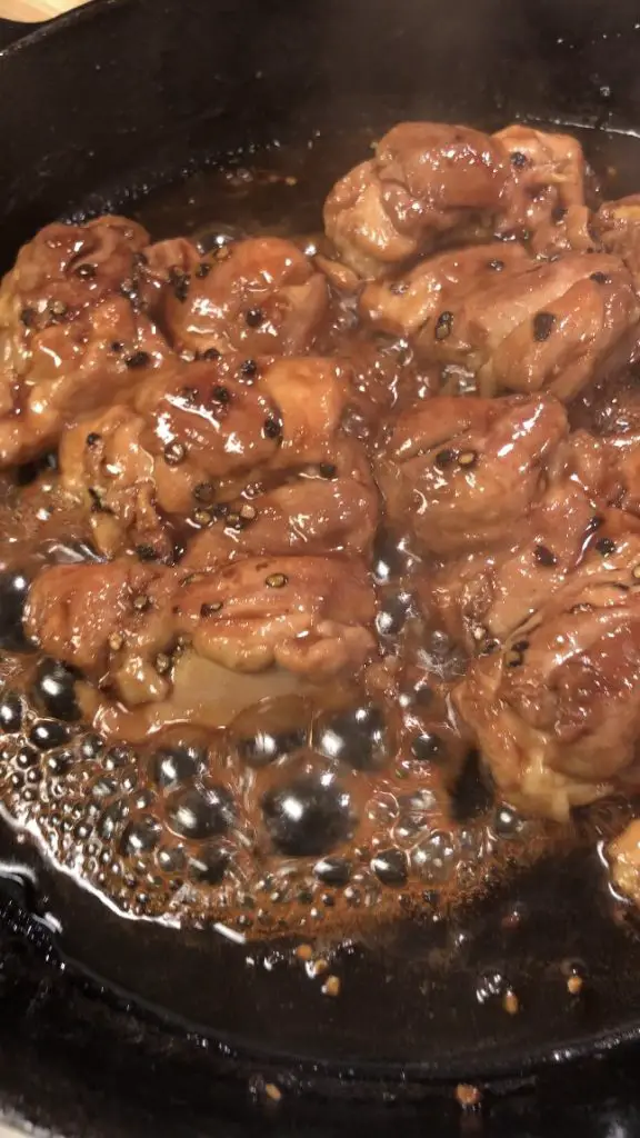 Teriyaki Chicken in a cast iron skillet with sauce becoming glossy as it reduces