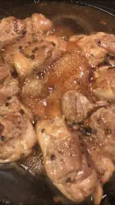 Teriyaki Chicken in a cast iron skillet with teriyaki sauce bubbling around it