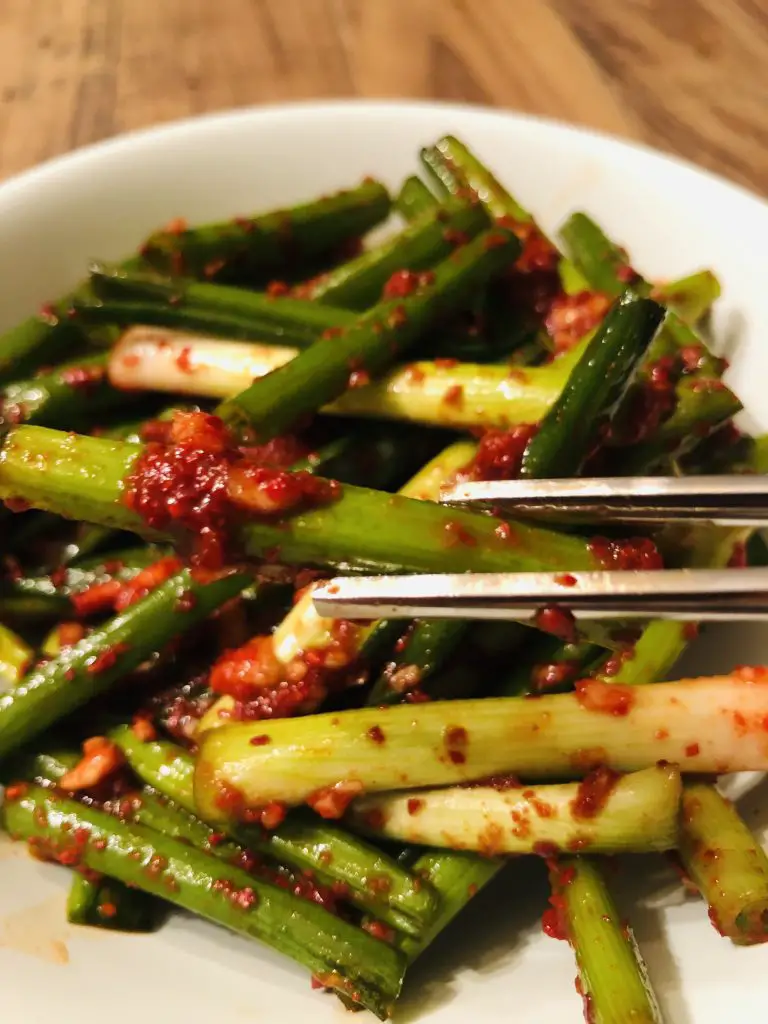 Green onion kimchi in a white bowl with silver chopsticks