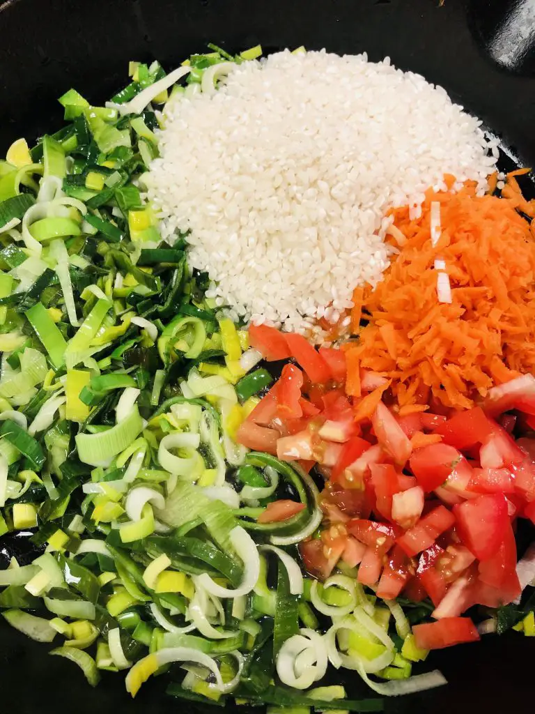 chopped leek, chopped tomatoes, grated carrot, and B Rice Kochani rice in a cast iron skillet