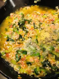 rice and vegetables in a broth in a cast iron skillet