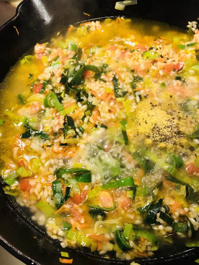 rice and vegetables in a broth in a cast iron skillet