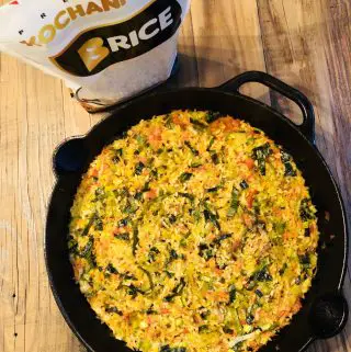 oven baked rice in a cast iron skillet with a bag of B Rice Kochani rice next to it