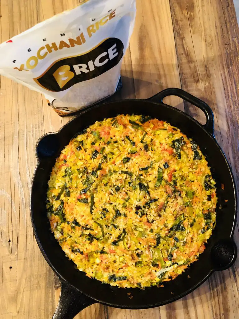 oven baked rice in a cast iron skillet with a bag of B Rice Kochani rice next to it
