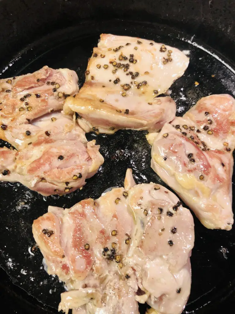 Boneless chicken breasts seasoned with pepper in a cast iron skillet