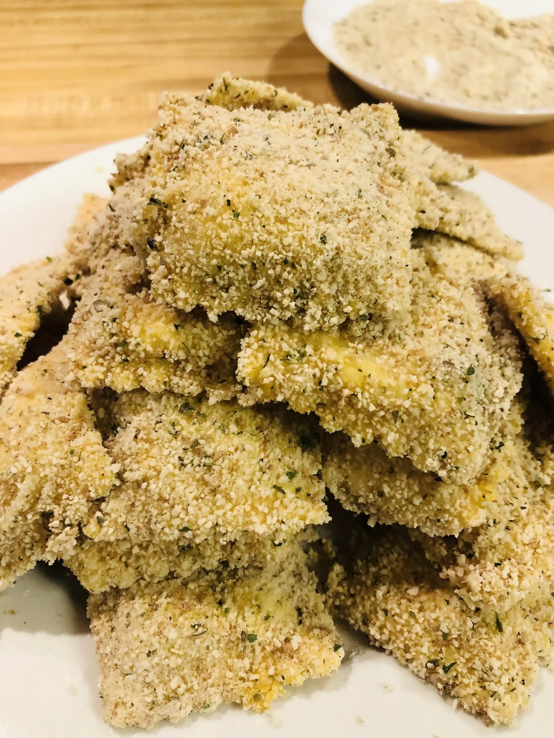 Ravioli which has been dredged in flour, egg, and breadcrumbs on a white plate