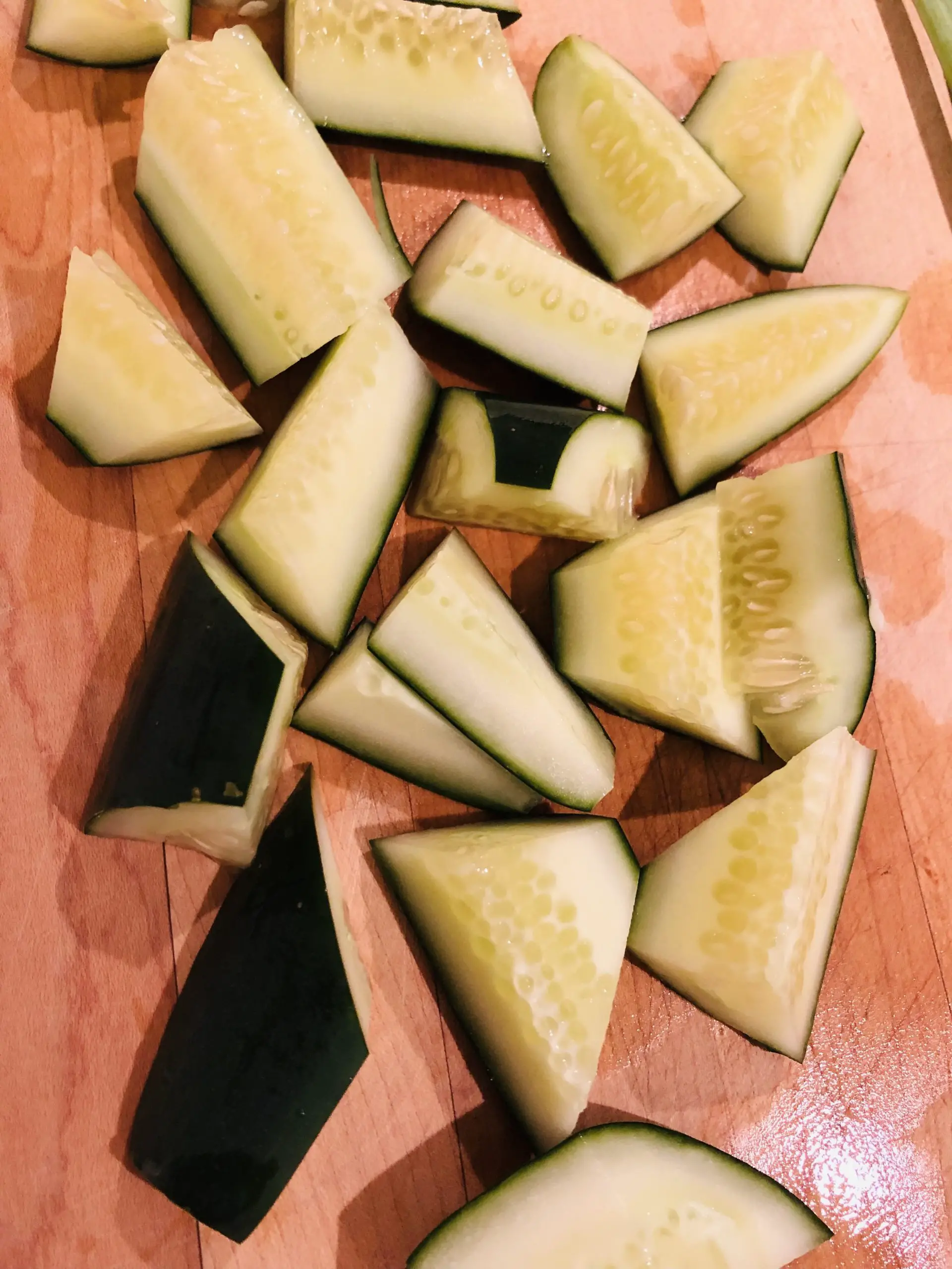cut up pieces of cucumber on a wooden board