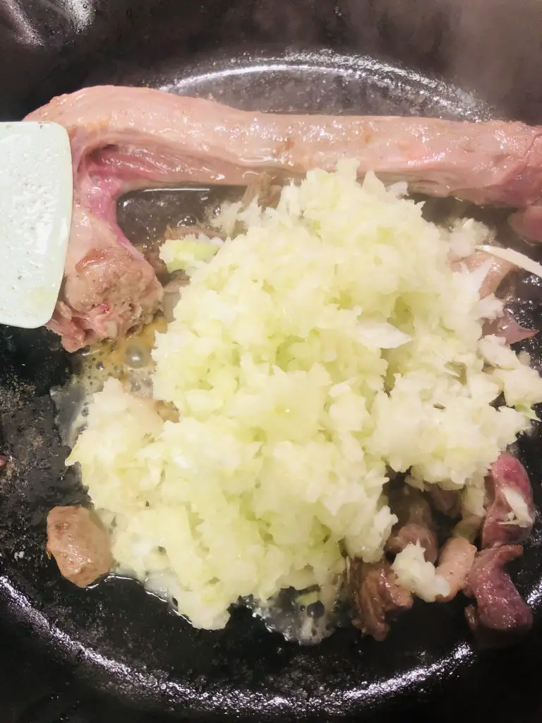 Goose neck and gizzards and chopped onion, garlic and celery in a skillet 