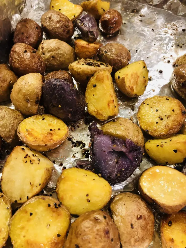 Roasted new potatoes seasoned with salt and pepper on a sheet of aluminum foil