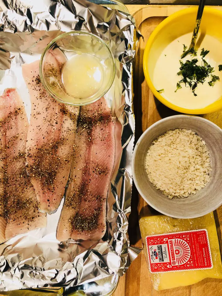 Rainbow trout fillets seasoned with pepper and salt, a bowl of lemon juice, panko in a white bowl, Emmenthaler cheese, dijon mustard, cream, and dill in a yellow bowl