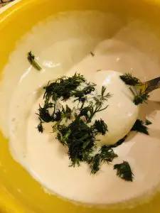 cream, mustard, and dill in a yellow bowl with a spoon